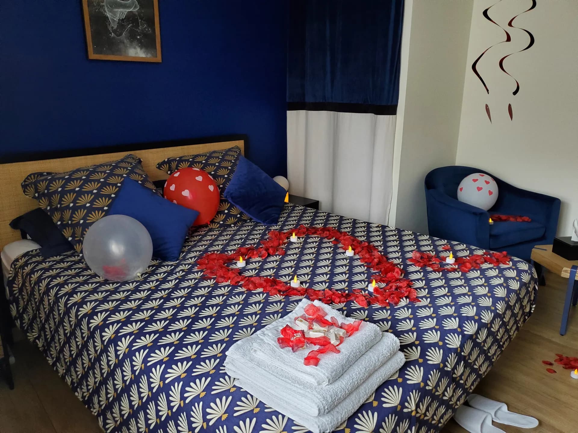 Lit décoré pour un week-end romantique : cœur de pétales, bougies et serviettes