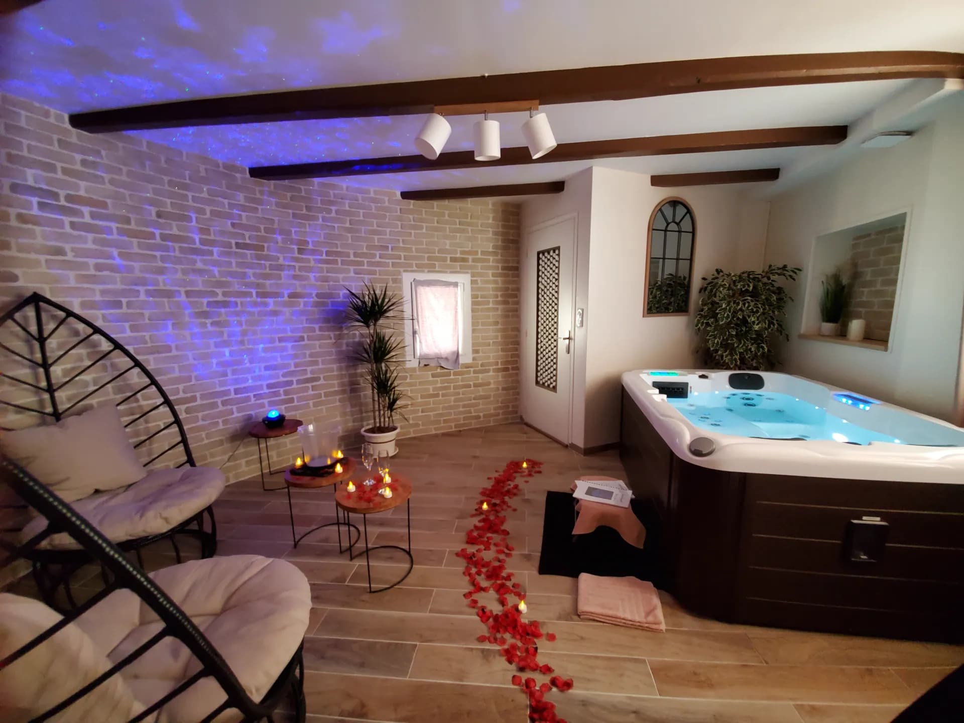 Pièce du spa privatif en décoration romantique : pétales de roses, bougies et ciel étoilé